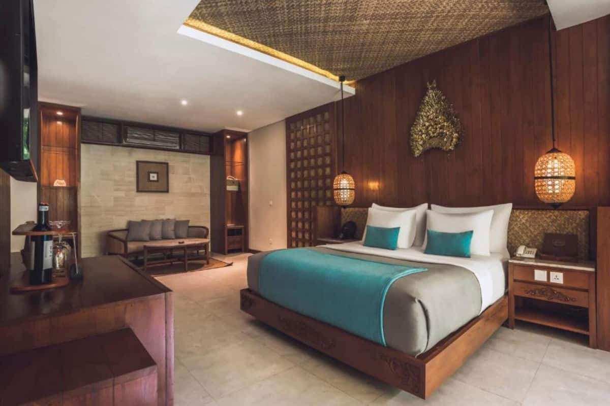 Een moderne hotelkamer met een groot bed, een bureau, een bank en een decoratief wandpaneel.