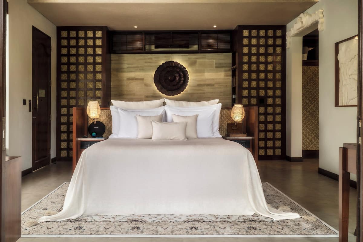 Een ruime slaapkamer met een groot bed, een decoratieve wand en twee bedlampen.
