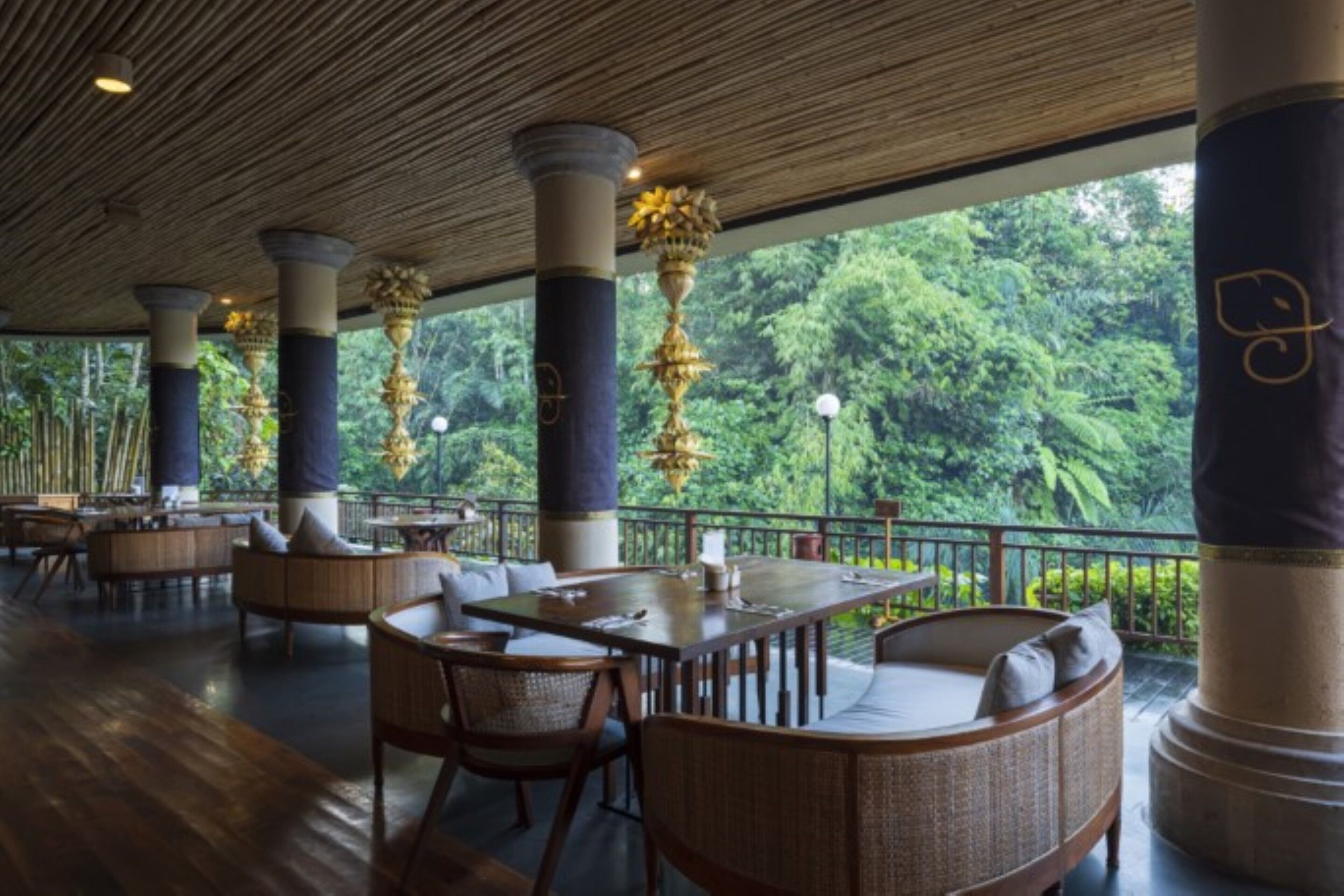 A spacious indoor area with wooden flooring, round tables, and wicker furniture.