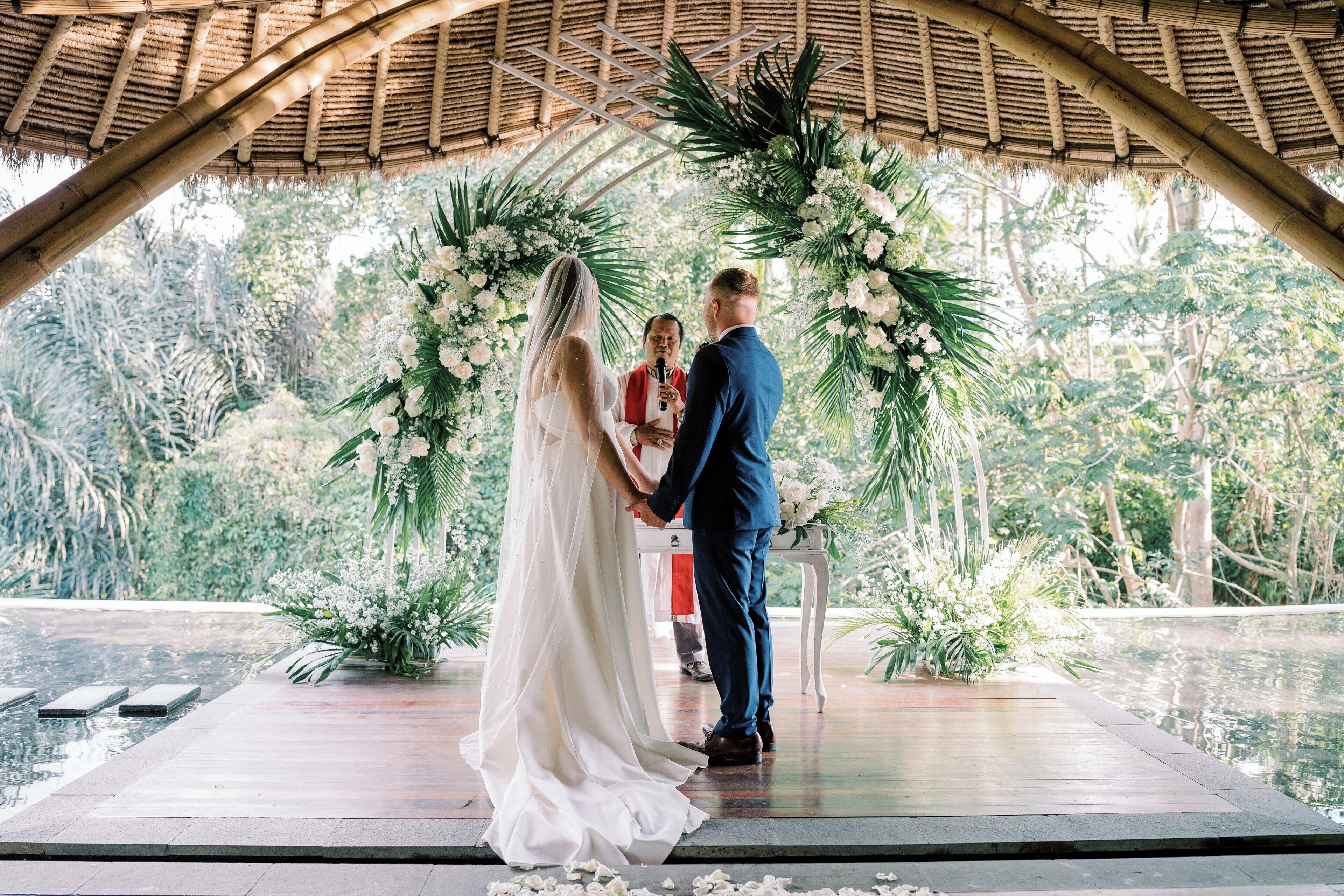 A wedding ceremony with a couple standing under a floral arch.