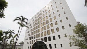 A modern building with a grid of windows and a central entrance. - Justice Hotel (Bangkok)