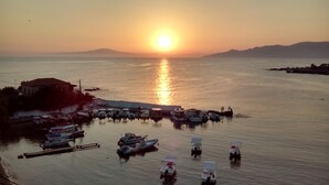 A marina with boats docked, a pier, and a sunset over the water.