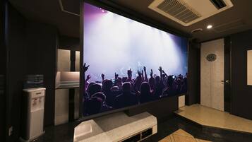 Un televisor de pantalla plana grande en un área de recepción, con un dispensador de agua y una pequeña zona de estar.