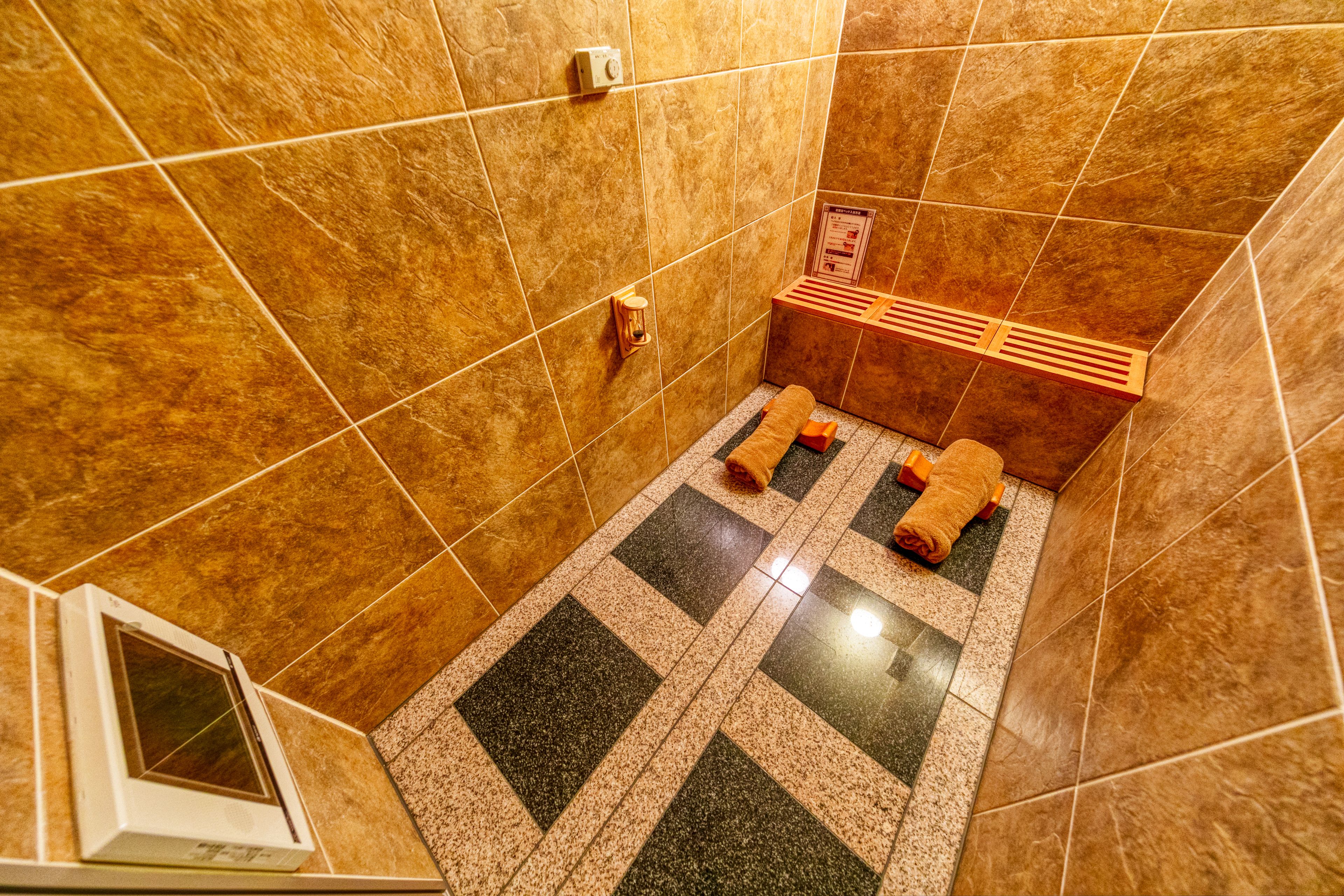 A small, tiled bathroom with a shower area, a towel rack, and a vent.