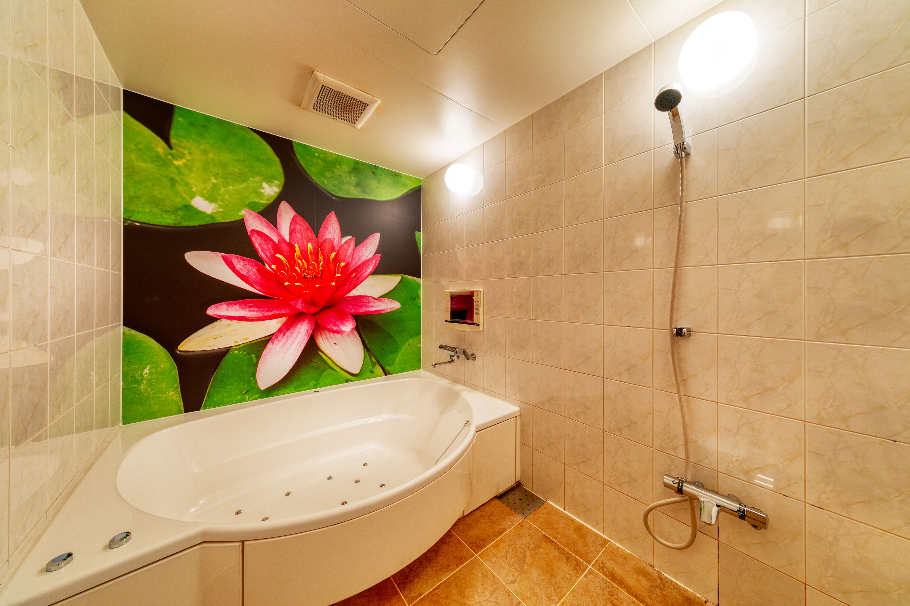 Une salle de bain avec une baignoire, une douche et une fresque murale représentant une fleur.
