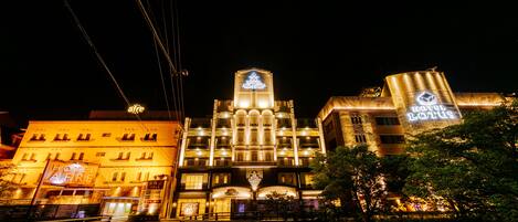 A hotel with a prominent tower, multiple balconies, and a well-lit facade.