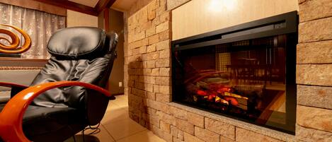A modern living room with a stone fireplace, leather recliner, and a decorative wall piece.