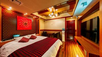 A hotel room with a large bed, a desk, and a TV.