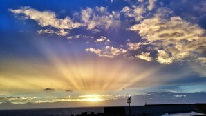 A sunset over the ocean with clouds, a street lamp, and buildings in the foreground. - White Sand Beach 32 (Lyudao)