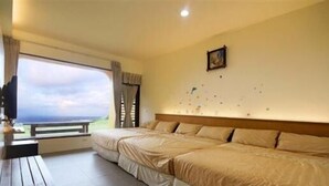 A bedroom with two beds, a large window with a view, and a small table. - White Sand Beach 32 (Lyudao)