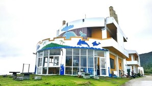 A multi-story building with a curved facade, large windows, and a blue dolphin mural. - White Sand Beach 32 (Lyudao)