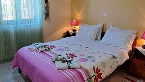 Un dormitorio con techo de madera, una cama con colcha rosa, un tapete a rayas y un cuadro en la pared.