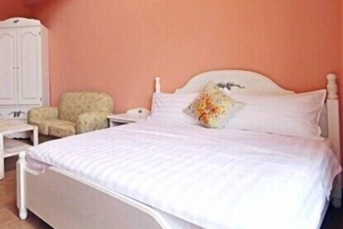 A bedroom with a bed, a nightstand, a chair, and a wardrobe.
