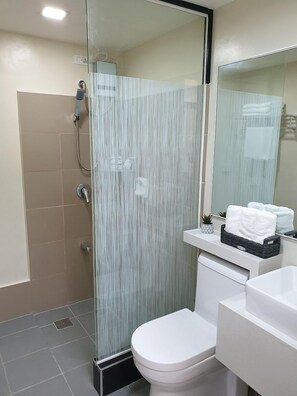 Une salle de bain moderne avec une douche à parois de verre, des toilettes blanches et un lavabo doté d’un porte-serviettes.