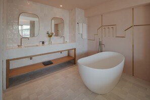 A modern bathroom with a freestanding bathtub, a vanity with a mirror, and a wooden bench.