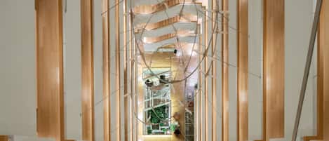 A modern architectural structure with wooden beams and white panels, featuring a central open space and multiple levels.