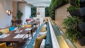 A modern dining area with a long bench, tables, and chairs. - COCO-MAT Athens BC (Athens)