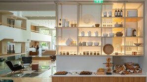 A modern hotel lobby with a reception desk, seating area, and a display of kitchenware and food items. - COCO-MAT Athens BC (Athens)