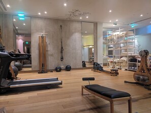 A gym with a treadmill, exercise balls, a bench, and a mirrored wall.