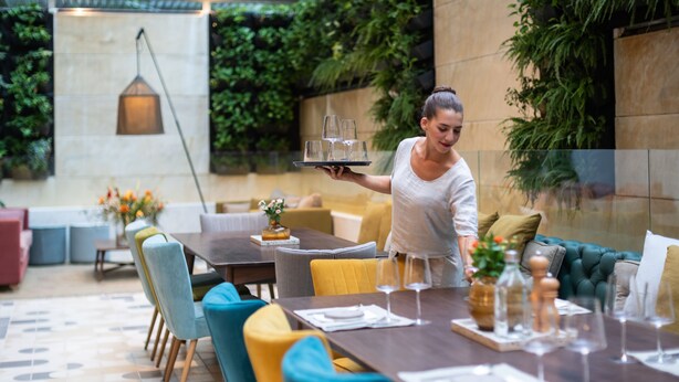 A dining area with a long table set for a meal, surrounded by colorful chairs. - COCO-MAT Athens BC (Athens)