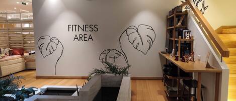 A fitness area with a wall mural, a hanging light, and a wooden staircase.