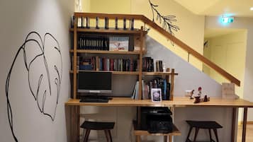 Una moderna biblioteca con scaffali, un grande schermo piatto e due sgabelli da bar.