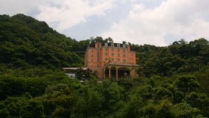 A large, multi-story building with a central courtyard, surrounded by dense greenery and hills. - Life Leisure Resort (Guanxi)