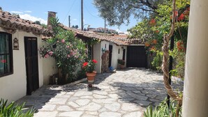 A narrow cobblestone courtyard with traditional architecture, including tiled roofs and white walls.