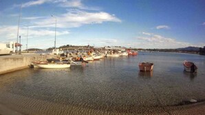 A marina with boats docked, a sandy shore, and a clear sky.
