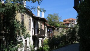 A traditional stone building with a balcony, surrounded by lush greenery.