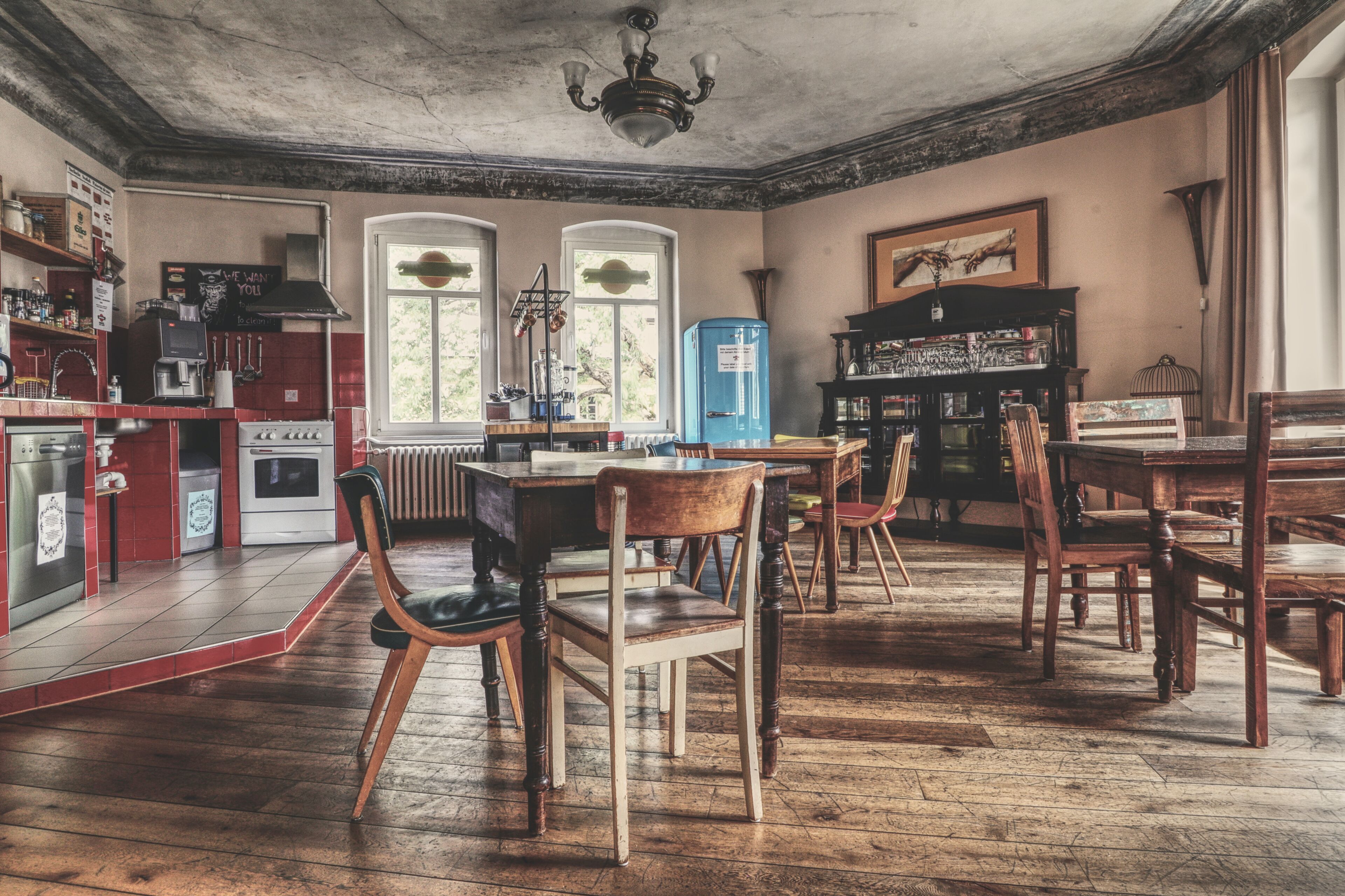 Une cuisine spacieuse avec un plancher en bois, un coin repas avec des chaises et un réfrigérateur bleu.