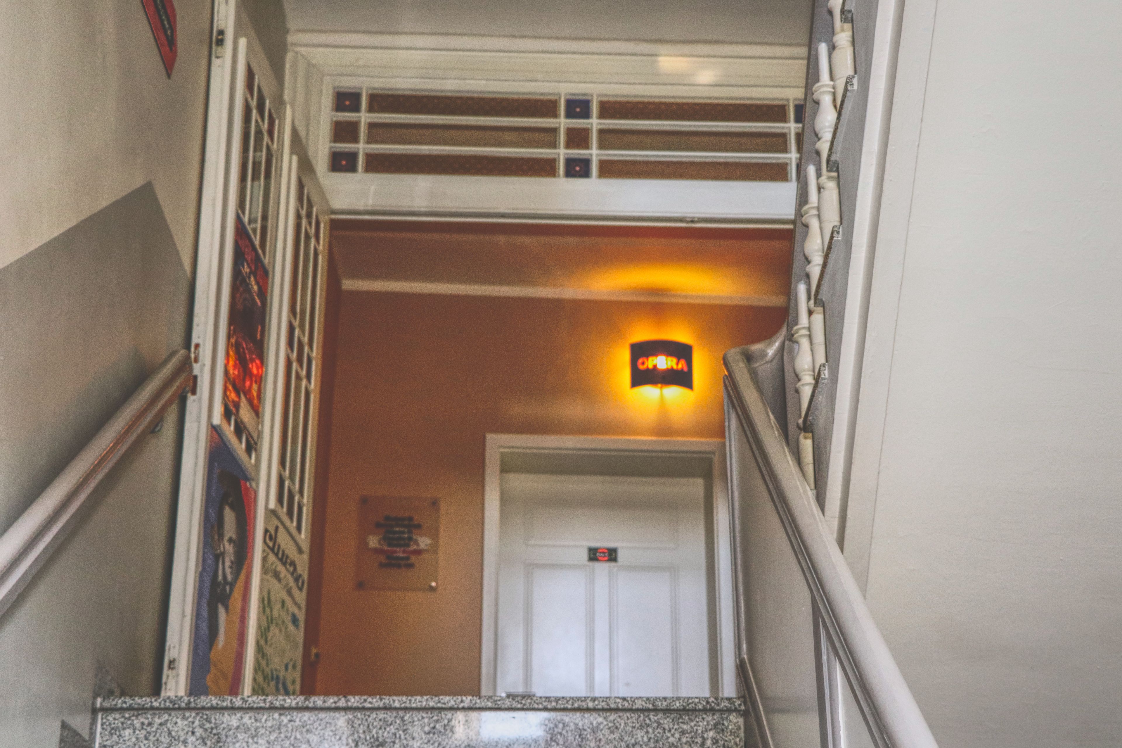Una escalera con barandilla, una lámpara sobre la puerta y un cartel en la pared.