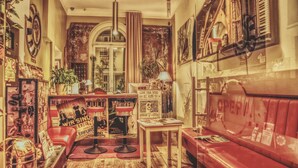 A cozy room with a red sofa, a small table, and a bar area with posters and a sign that reads "Leave Your Mind at Home". - OPERA Hostel (Erfurt)