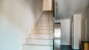 A staircase with a glass railing leading to a landing with a door. - bikehikesleep (Sasbachwalden)