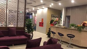 A reception area with purple sofas, a reception desk, and a potted plant. - Starway Hotel (Ha Long)