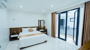 A modern hotel room with a large bed, a bedside table, a mirror, and a sliding glass door to a balcony. - Starway Hotel (Ha Long)