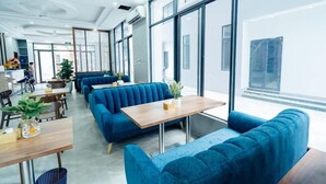 A modern interior with blue upholstered seating, wooden tables, and large windows. - Starway Hotel (Ha Long)