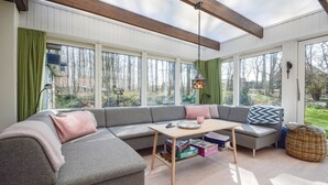 A cozy living room with a grey sectional sofa, a wooden coffee table, and a view of a forest through large windows. - Awesome home in Haderslev with WiFi (Haderslev)