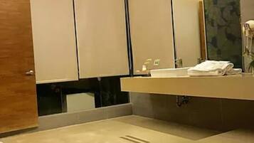 A modern bathroom with a large mirror, a sink, and a towel on the counter.