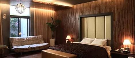 Un dormitorio con una cama grande, zona de estar y una ventana.