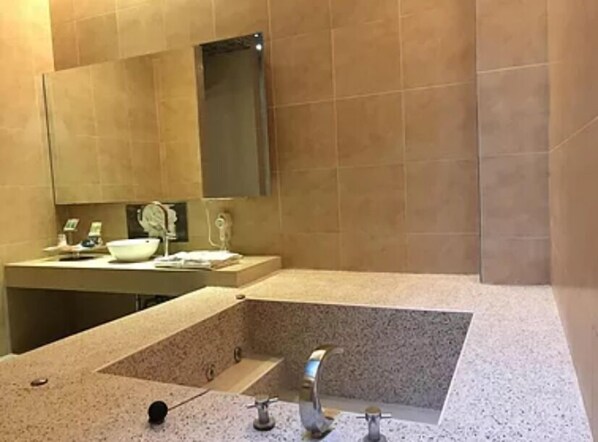 Un baño con un lavamanos grande, un espejo y una bañera.