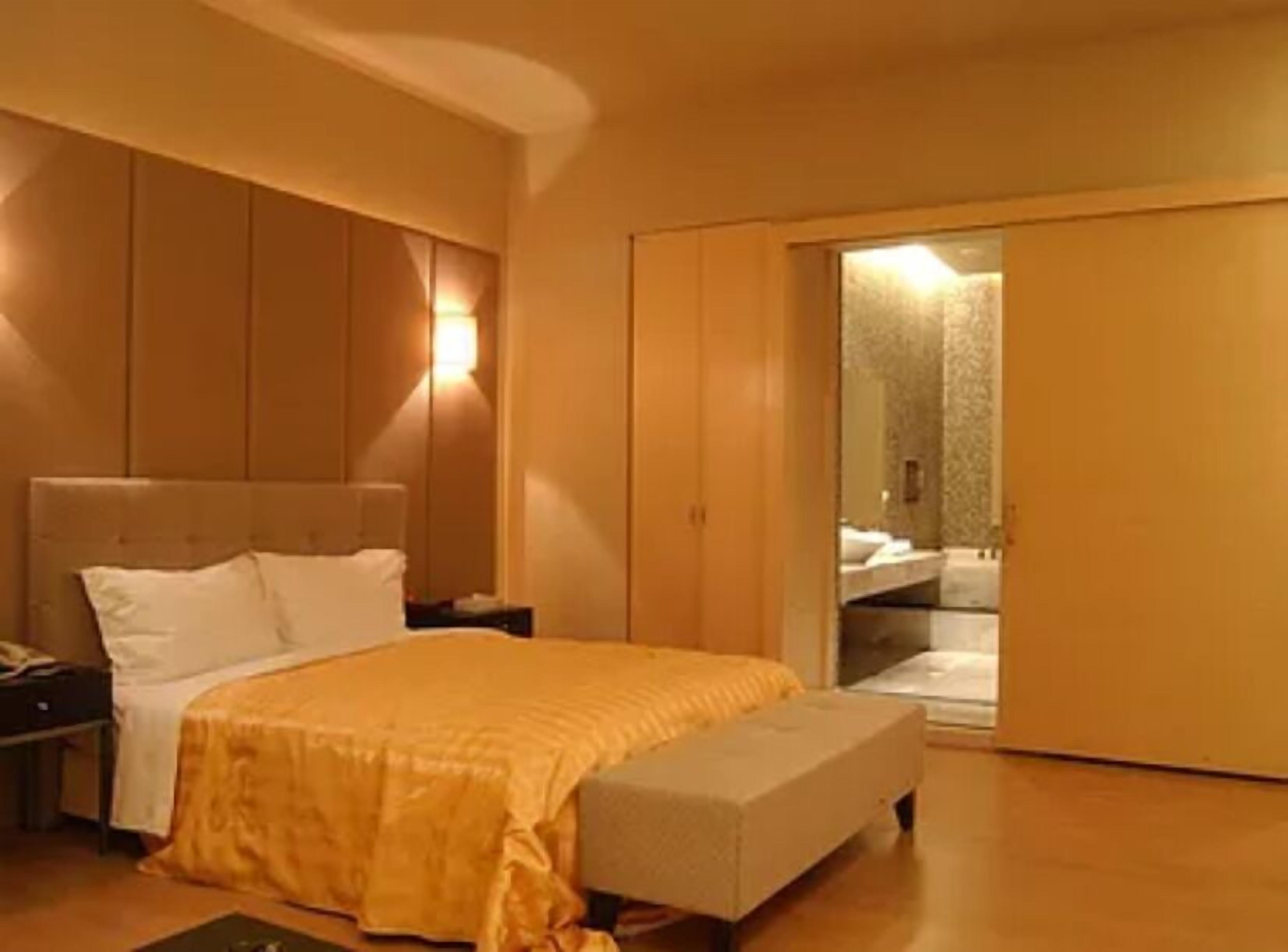 Ein Schlafzimmer mit Bett, Nachttischen, einer Bank und einem Kleiderschrank.