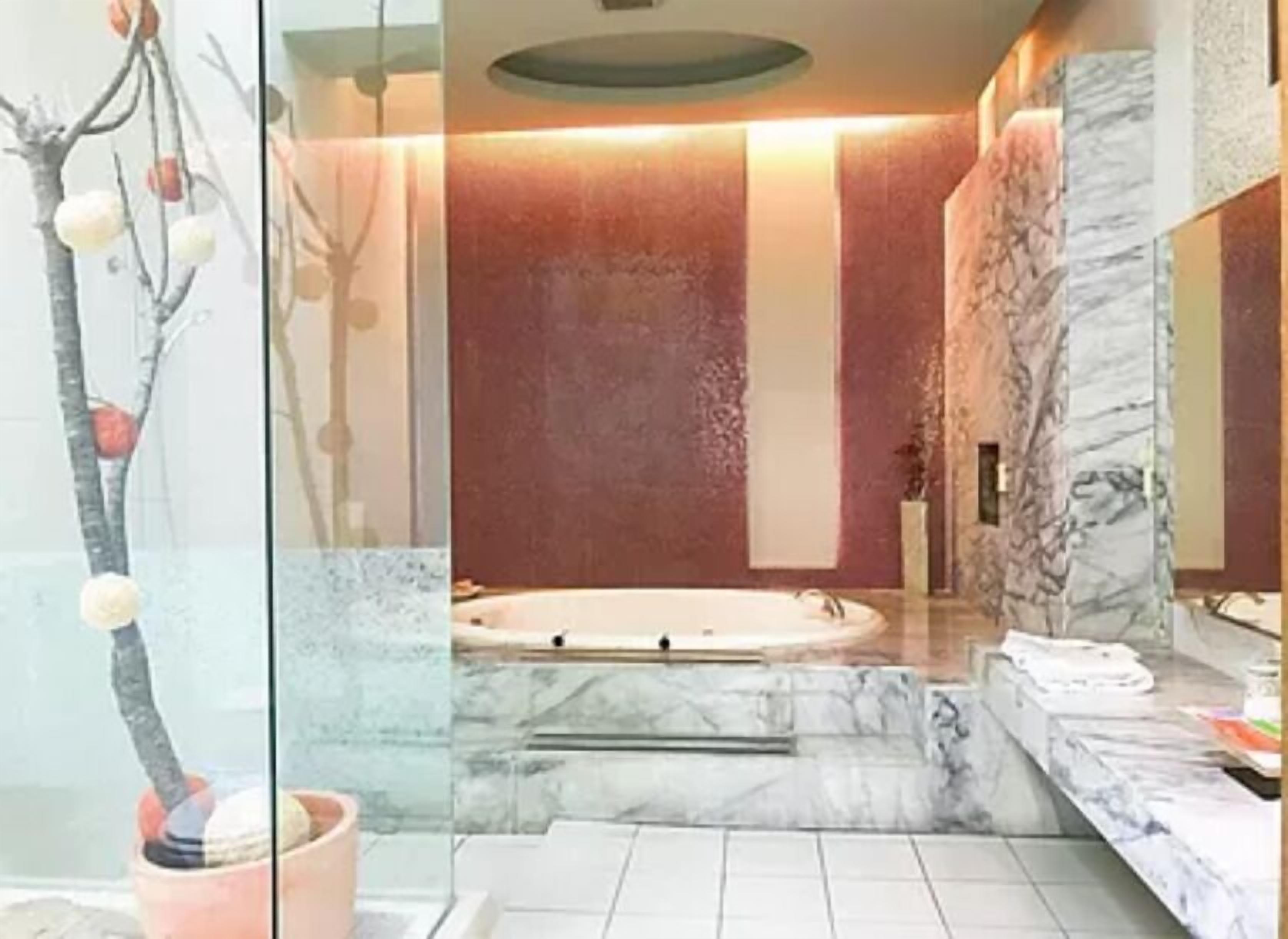 A bathroom with a marble floor, a bathtub, and a potted plant.
