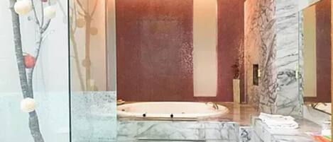 A bathroom with a marble floor, a bathtub, and a potted plant.