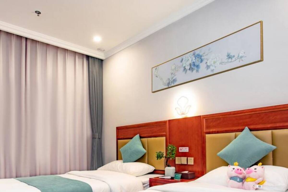 Habitación de hotel con dos camas, cabecera de madera, un cuadro, mesita de noche y una figurita decorativa de un cerdo.