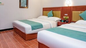 Une chambre d’hôtel avec deux lits, une tête de lit en bois, une table de chevet avec une lampe et un tableau encadré au mur.