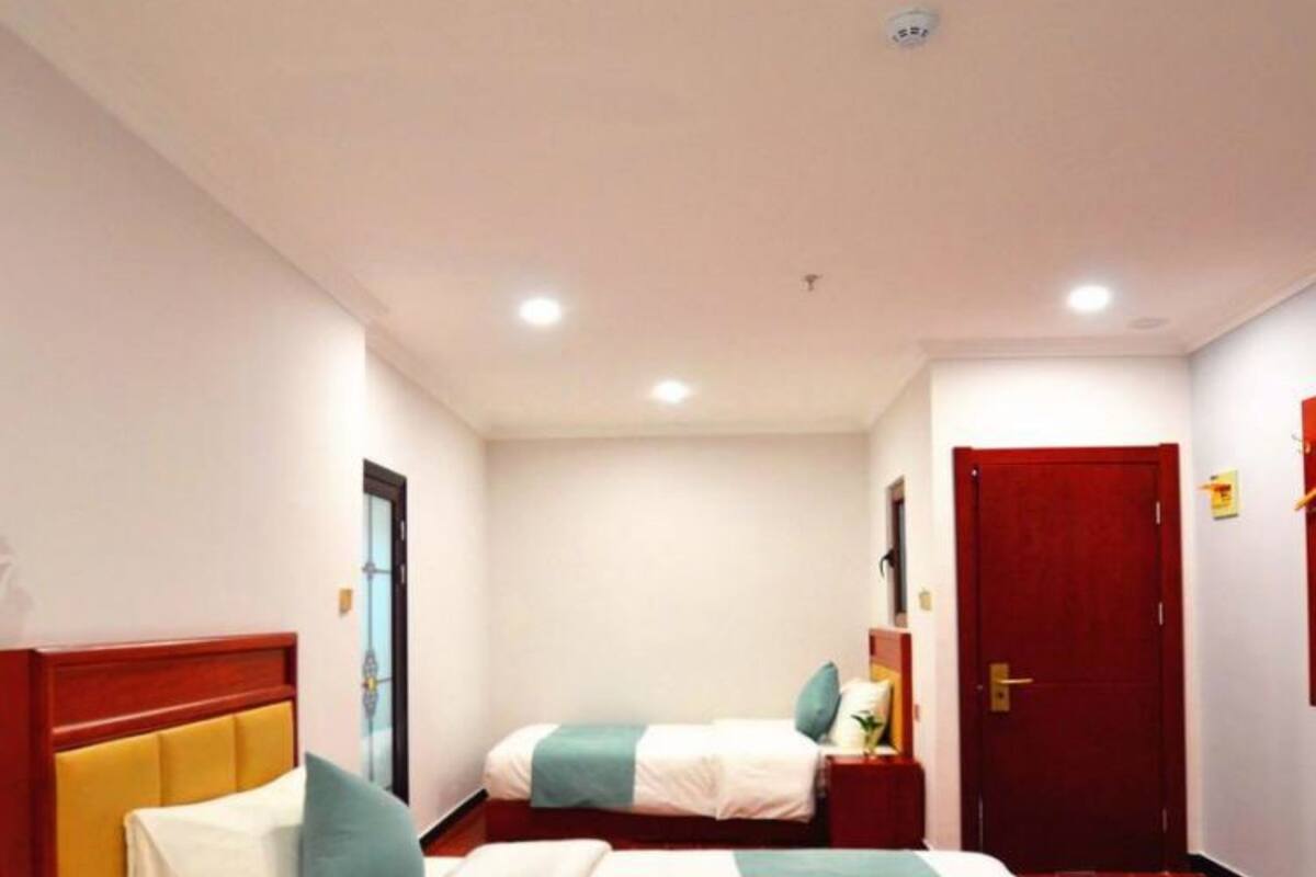 Habitación de hotel con dos camas, una puerta roja y una mesita de noche pequeña.