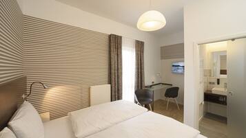 Ein Hotelzimmer mit einem großen Bett, einem Schreibtisch, einem Sessel, einem Fernseher und einem Badezimmer.