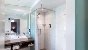 A modern bathroom with a white sink, mirror, and shower.