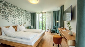 A modern hotel room with a wooden bed, a desk with a chair, a TV, and a large window with curtains.